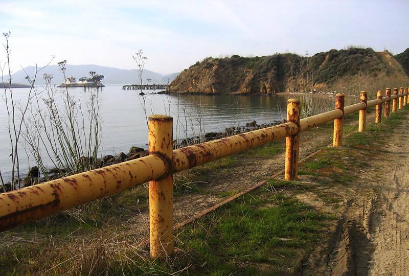 The beach to left of railing, island in the distance