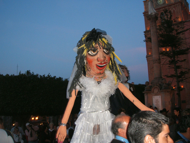 enormous bride and groom puppets waiting outside a  wedding in the Parroquia