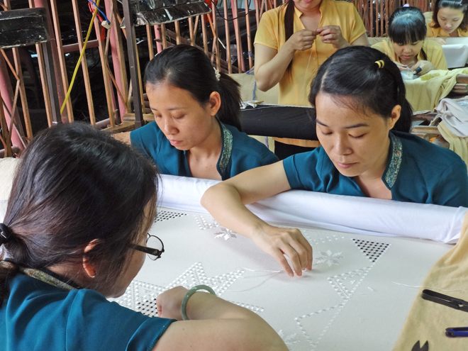 Artisans embroidering a table cloth at the Thang Loi Company, Hoi An, Vietnam