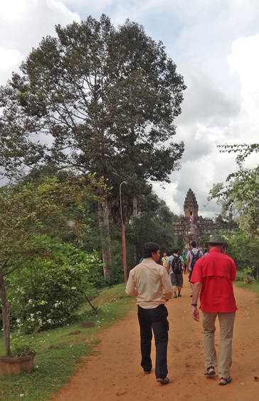 Alan and our groups guide Borin walking toward the 9th century c.e. Bakong Temple (background) in the Roluos Group, Cambodia