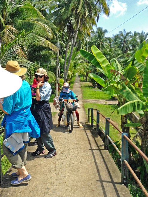  A local  on a motorized cycle, Judy and Stacy on a trail on a island near My Tho, Vietnam