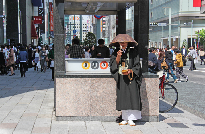 A man who appears to be a monk or priest soliciting donations in Ginza - traditional and modern Japan cross paths