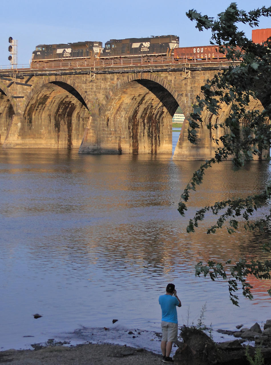 Mr. Odell shoots from the riverbank as a Eastbound train starts out on the bridge just before dark 