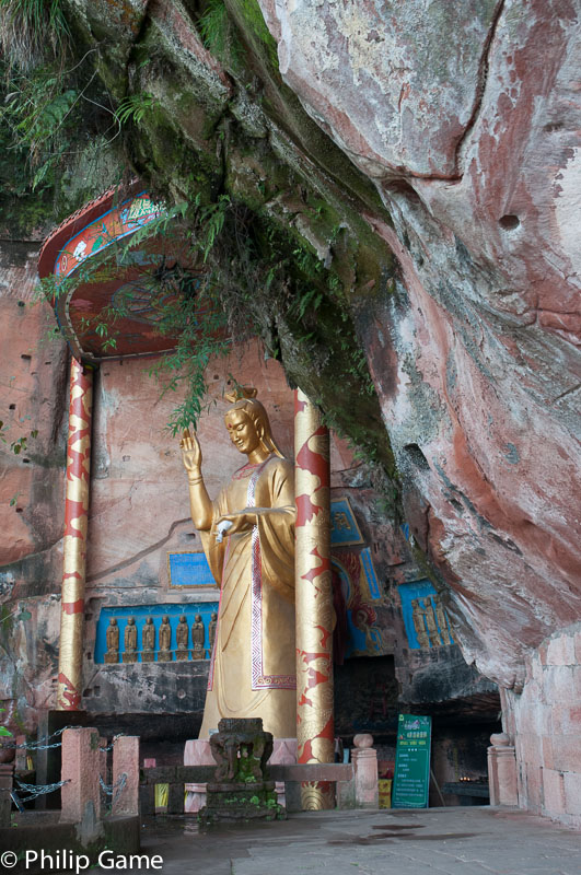 Buddha effigy tucked under a cliff overhang