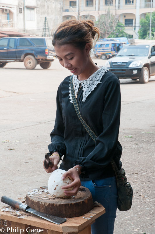 Young woman dicing coconuts in the Pakse market