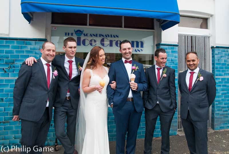 A wedding party hamming it up outside an ice-creamery