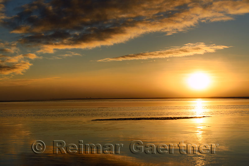 Setting sun over calm water of the Beaufort Sea at Barter Island Kaktovik Alaska