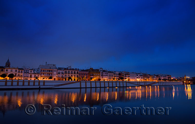 Houses on Betis street to Isabel bridge Seville reflected at dawn in Alfonso XIII Canal