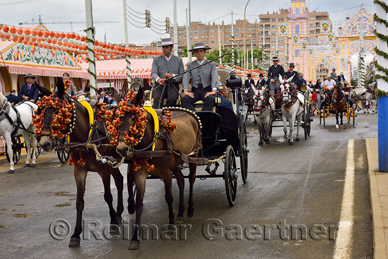 Mule teams pulling carriages with casetas and the Main Gate 2015 Seville April Fair
