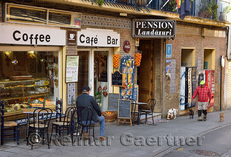 Man walking dogs and early morning street scene at cafe in Granada Spain