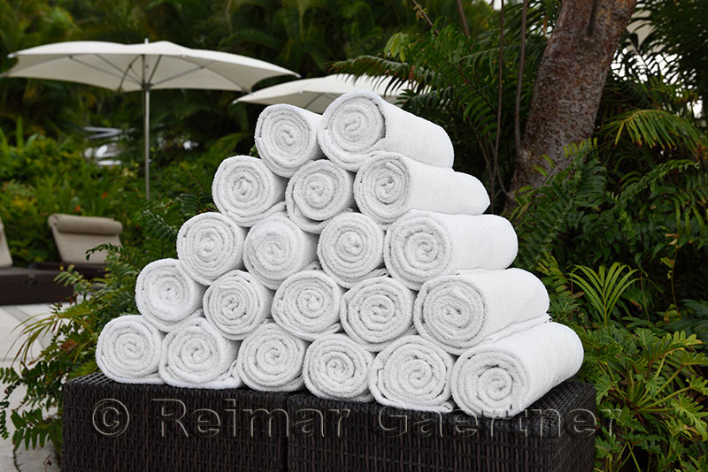 Stack of rolled up towels in a shaded tropical garden resort