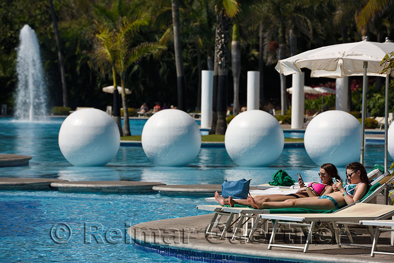 Two young woman lounging by the pool in Nuevo Vallarta Mexico
