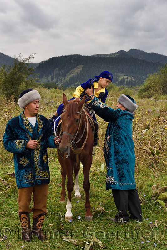 Sundet Toi circumcision with boy on horse and men in traditional Kazakh shapan coat and borik hat