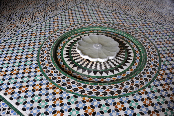 Another small marble fountain set on a floor of zellige tile