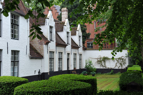 White washed brick houses with a small lawn at the south end of the Begijnhof, Bruges