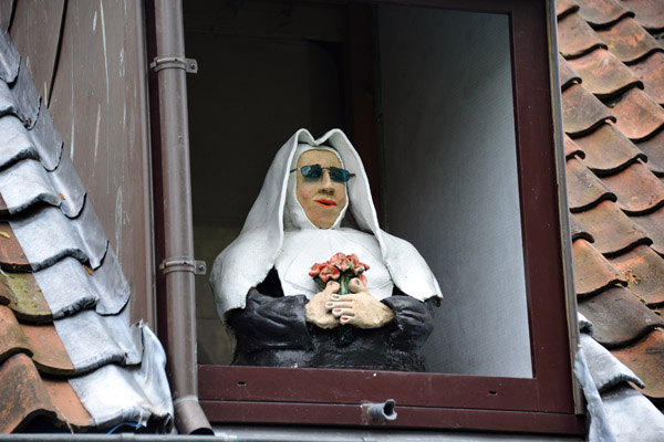 Nun with sunglasses inside a window of the Begijnhof