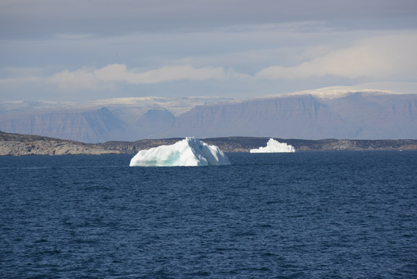 The first small icebergs are spotted with Disko Island in the distance