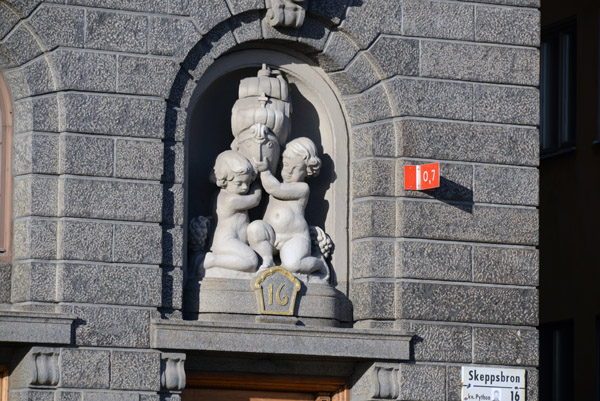Cherubs holding a sailing ship, Simsonship AB, Skeppsbron 16