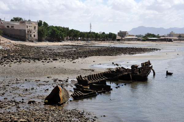 Wreck of a small boat along the beach by the pier, Berbera