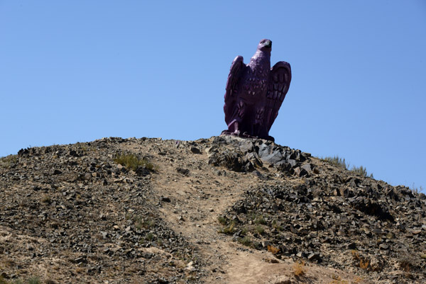 Statue of an eagle on a roadside hill