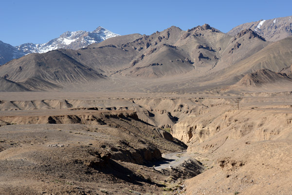 A small canyon with some of the high Pamir peaks in the distance
