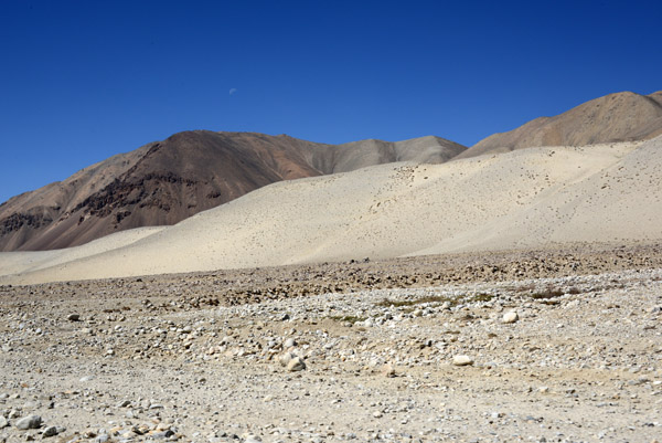 Sand dunes at the base of the mountains covering the rock desert floor