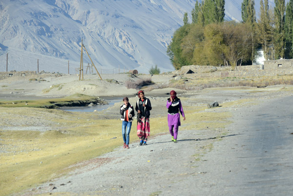 Three girls walking along the Wakhan Valley road, Tajikistan