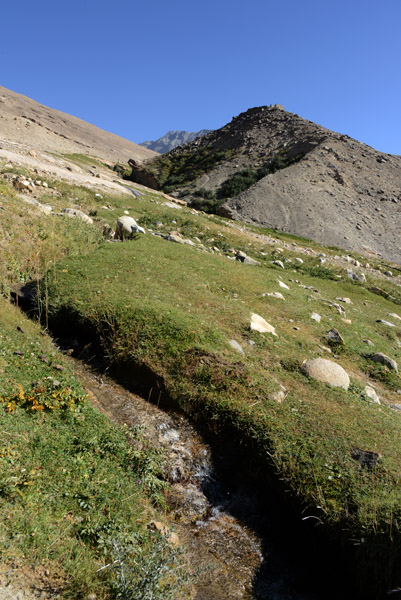 A tiny stream cut through the grassy turf clinging to the mountainside