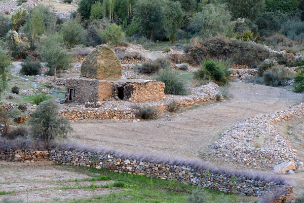 Primitive house in a village on the Afghanistan side of the Panj River with a large pile of hay on the roof