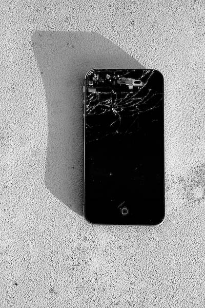 Dead iPhone atop a telephone utility box by the sidewalk