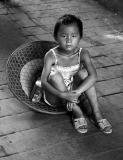 A hot a humid day for a small girl. She found relief by sitting in a hat in the shade.