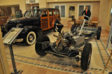 1938 Oldsmobile display chassis, photographed through glass window of car dealership showroom