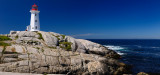 Peggys Cove Nova Scotia lighthouse on worn granite rocks with accordian player tourists and surf