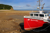Young girl walking on Ocean floor next to an achored boat on the Bay of Fundy Alma New Brunswick