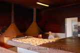 Moroccan woman baking bread in a wood burning oven early in the morning at El Jedida