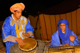 Blue Berber tuareg men playing djembe and bongo drums at night in Erg Chebbi desert Morocco