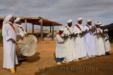 Group of Gnawa musicians in white robes dancing and playing krakeb and drum in Khemliya Morocco