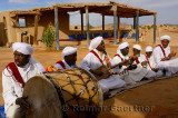 Gnawa musicians singing and playing while sitting in the desert street of Khemliya Morocco