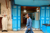 Moroccan man watching men walking by in djellabas and caps in blue Fes el Bali medina Morocco