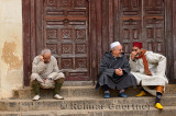 Two Moroccan men talking laughing one sitting apart at the steps to the north entrance of Andalusian Mosque