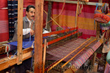 Fast moving weaver operating a horizontal wooden hand loom in a cloth shop Fes el Bali Morocco