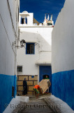 Young men moving a refrigerator through a small blue door in the narrow alley of Oudaia Kasbah Rabat Morocco