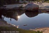 Sun being revealed behind Cathedral Peak in reflection