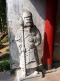 A stone Vietnamese warrior inside the Quan Thanh Temple.