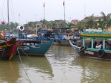 A mix of wooden tourist boats and fishing boats on the Thu Bon River.