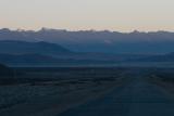 Sunlight on the mountaintops in the distance with the Qinghai-Tibet road and railway stretching out below.