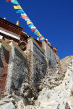 Steep wall of the hillside monastery with prayer flags