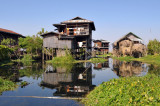 Stilt house reflected in the mirror smooth later of Inle Lake