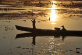 Poling an Inle Lake long boat with the reflection of sunset