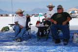 Three gents watching the speeding vehicles go by